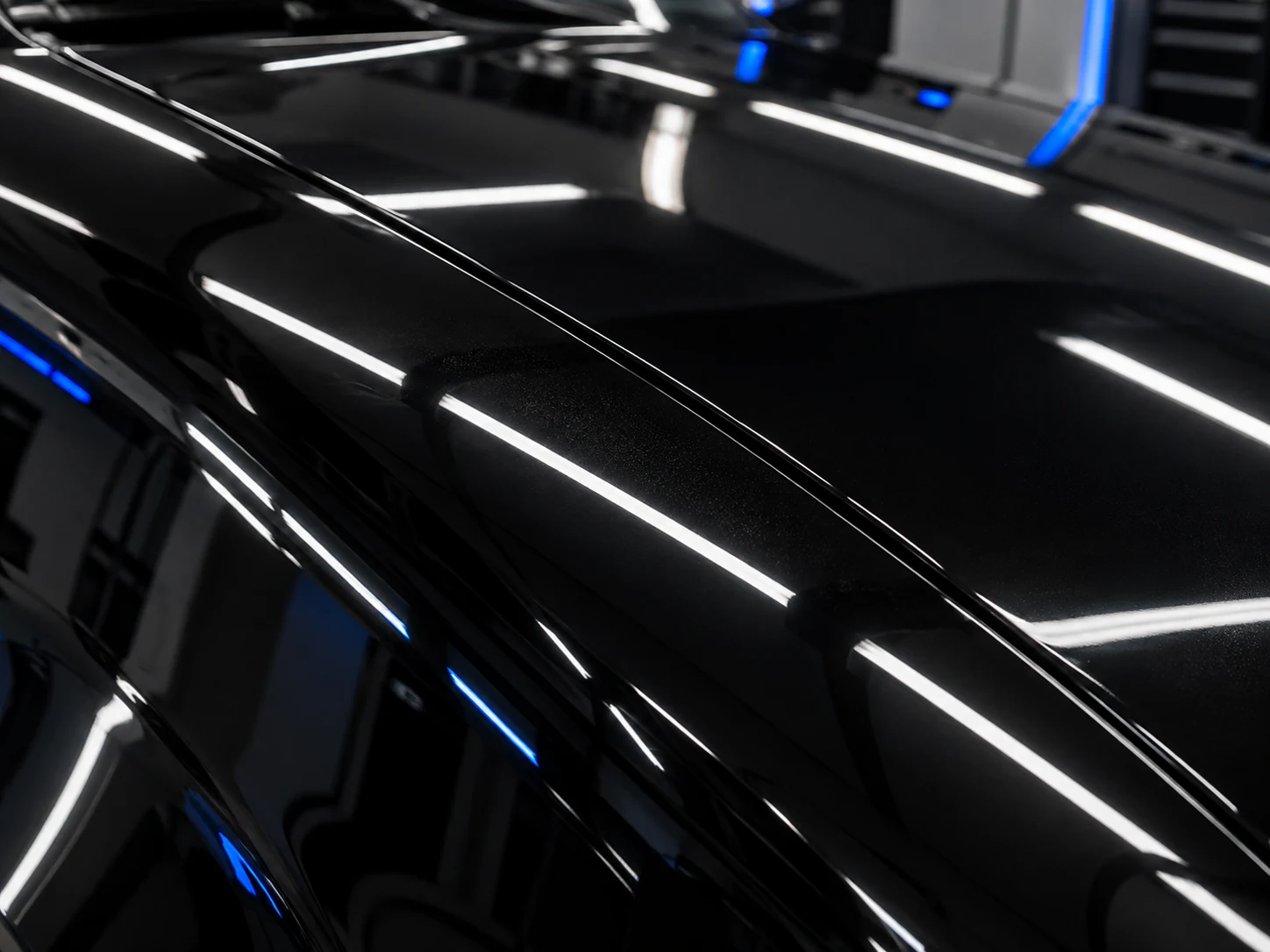 Ultra close-up mirror-finish shot of glossy black paint and hood reflections